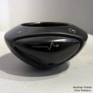 Bear carved into a black bowl decorated with a sgraffito heart line and bear paw design