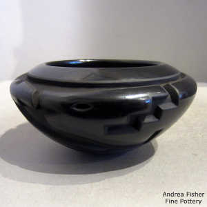 An avanyu and kiva step design carved into a black bowl