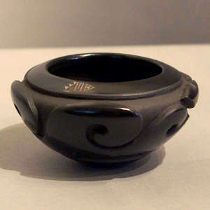 Sgraffito on rim and water wave design carved into a polished black bowl