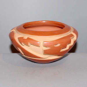 An avanyu design carved into a polished red bowl