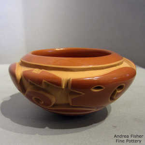 An avanyu design carved into a red bowl