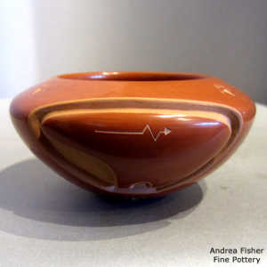 Sgraffito heart line and bear paws on a red bowl carved with a bear