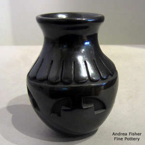 Feather and geometric design carved into a black jar