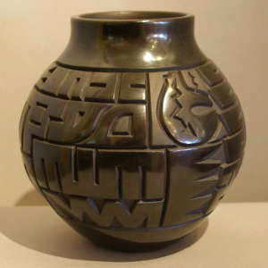 Bear with heart line and geometric design carved into a polished black jar