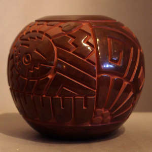 Katsina face and geometric design carved into a brown jar