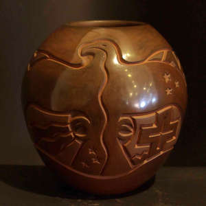 Thunderbird, eagle, cross and star design carved into a polished brown jar