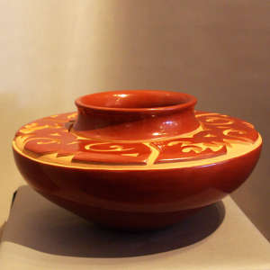 Geometric design carved into a polished red flat-topped jar