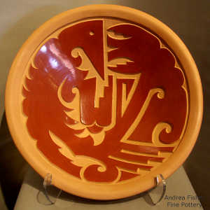 Stylized hummingbird and geometric design carved into a polished red bowl