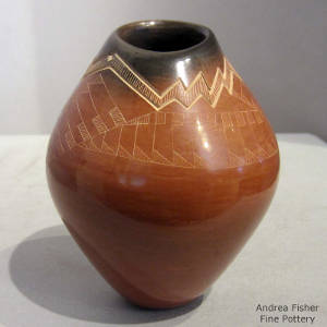 Sgraffito geometric design on a brown jar with a black rim and an organic opening