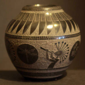 Sgraffito kokopelli, feather and dragonfly design on a black jar