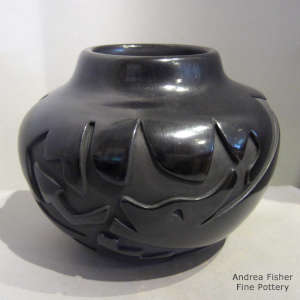 An avanyu design carved into a black jar