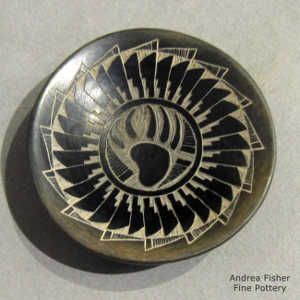 Sgraffito bear paw, feather and geometric design on a black plate