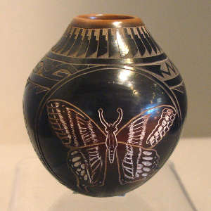Sgraffito feather, avanyu, butterfly and geometric design on a black jar with sienna rim