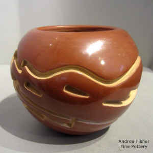 An avanyu design carved into a red jar
