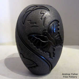 Micaceous black background on a black jar carved with polished butterflies and geometric design