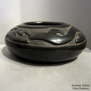 An avanyu design carved into a low shouldered black jar