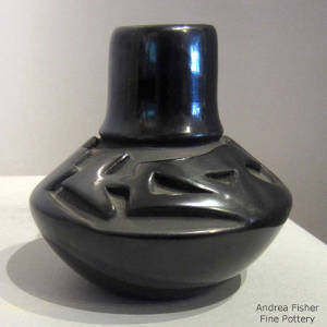Avanyu design carved into a long neck black jar