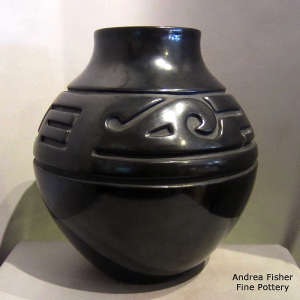 An avanyu and geometric design carved into a black jar