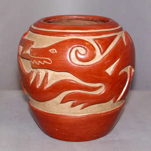 An avanyu design carved into a red jar