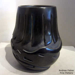 An avanyu and feather design carved into a black jar