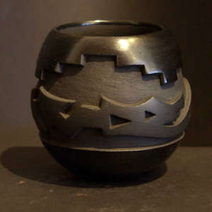 An avanyu design carved into a black on black jar