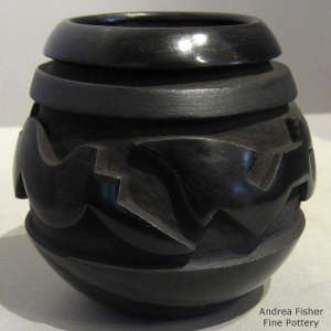 An avanyu design carved into a black on black jar