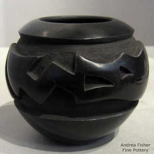An avanyu design carved into a black jar