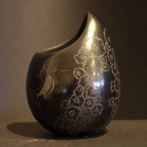 Sgraffito hummingbuiird and hollyhocks design on a polished black jar with an organic opening