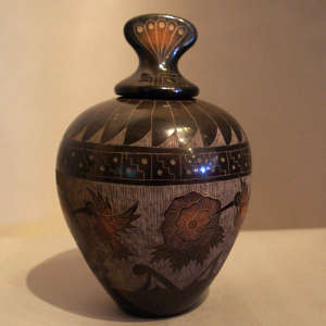 Sgraffito hummingbird, floral and geometric design on a lidded black jar