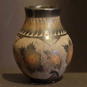 Sgraffito flower, butterfly and feather design on a black jar with sienna spots