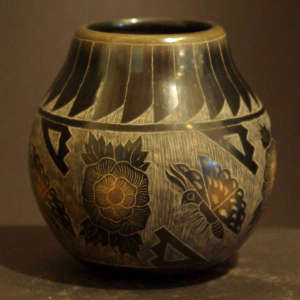 Sgraffito butterfly, flower and geometric design on a black jar with sienna spots