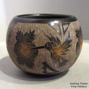 Sgraffito hummingbird, flower and geometric design on a black jar with sienna spots