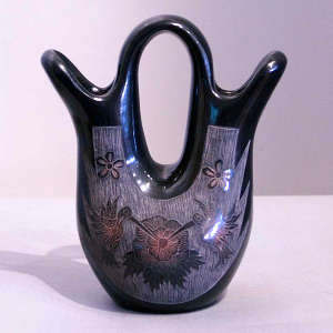 Sgraffito hummingbird, butterfly, flower and geometric design on a black jar with sienna spots