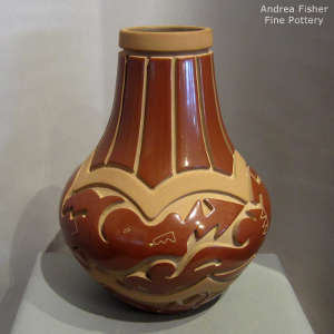 Avanyu and geometric design carved into a red and buff jar