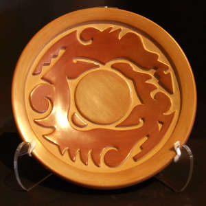 Avanyu design carved into a red and tan plate