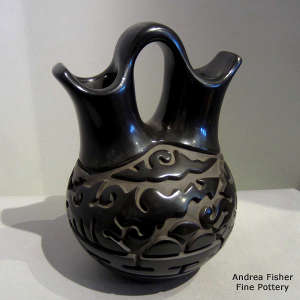 An avanyu and geometric design carved into a black wedding vase