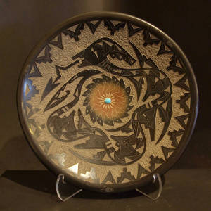 Sgraffito avanyu, kiva step and geometric designs on a black plate with a sienna spot and inlaid turquoise