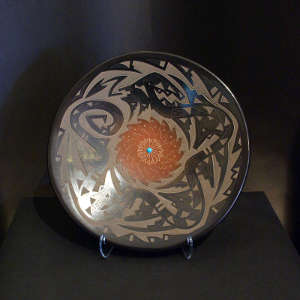 Sgraffito avanyu and geometric design on a black plate with sienna center and inlaid stone