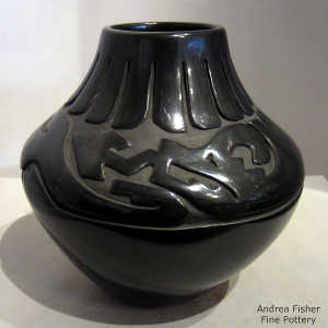 An avanyu and feather design carved into a black jar