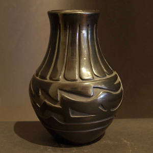 Feather and avanyu designs carved into a tall neck black jar