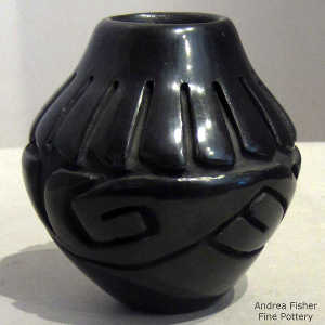 Stylized avanyu and feather design carved into a black jar