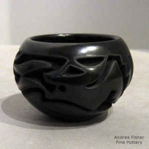 An avanyu design carved into a miniature black jar