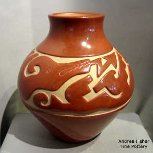 An avanyu design carved into a red jar