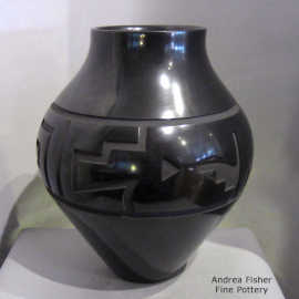 A stylized avanyu design carved into a black jar