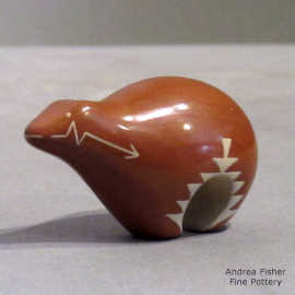 A miniature red bear figure with a geometric design