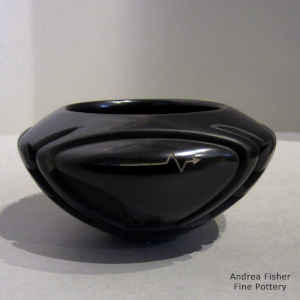 Bear and geometric design carved into a black bowl, with a sgraffito heart line