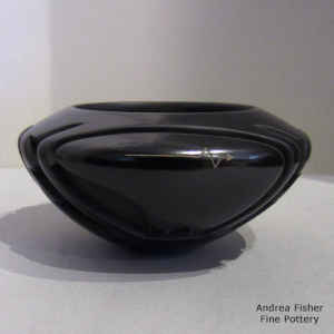 Bear and geometric design carved into a black bowl with sgraffito heart line and bear paws