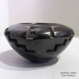 Eagle and geometric design carved into a black bowl with sgraffito bear paws