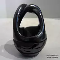 Black freiendship basket with twisted handles and carved with an avanyu design