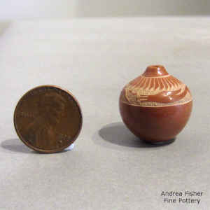 Miniature red jar decorated with a sgraffito avanyu and feather design